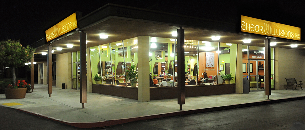 Illuminated Shear Illusions Salon & Spa storefront at night